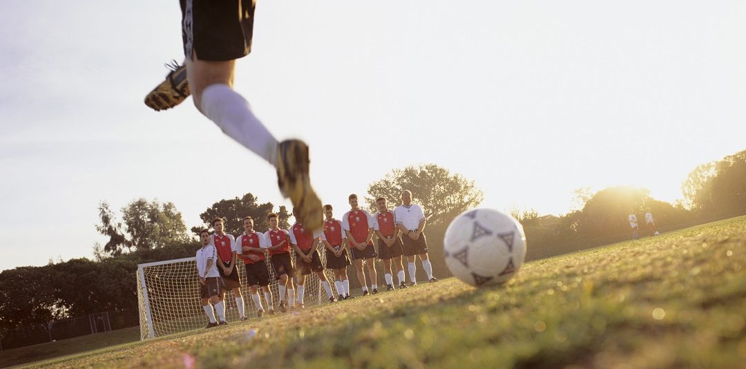 Footballer taking penalty at game, low section, surface view