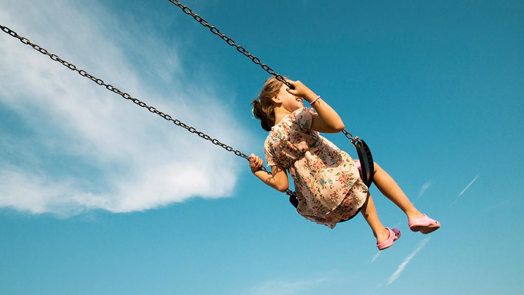 Little Girl Swinging Against Blue Sky