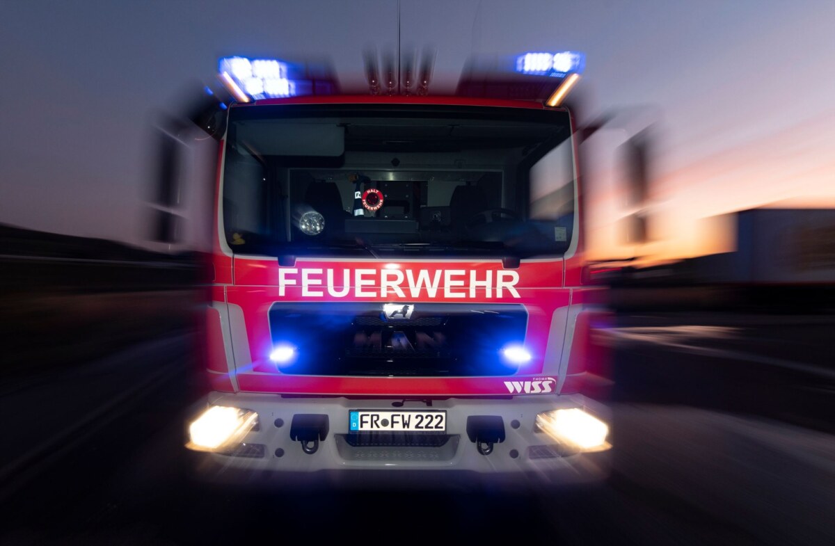 Ein Feuerwehrfahrzeug steht mit eingeschaltetem Blaulicht auf einer Straße.