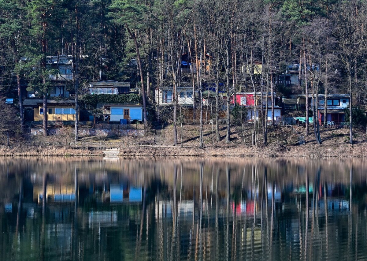 Blick über den Schervenzsee im Naturpark Schlaubetal auf kleine Hütten auf dem Gelände des Campingplatzes.