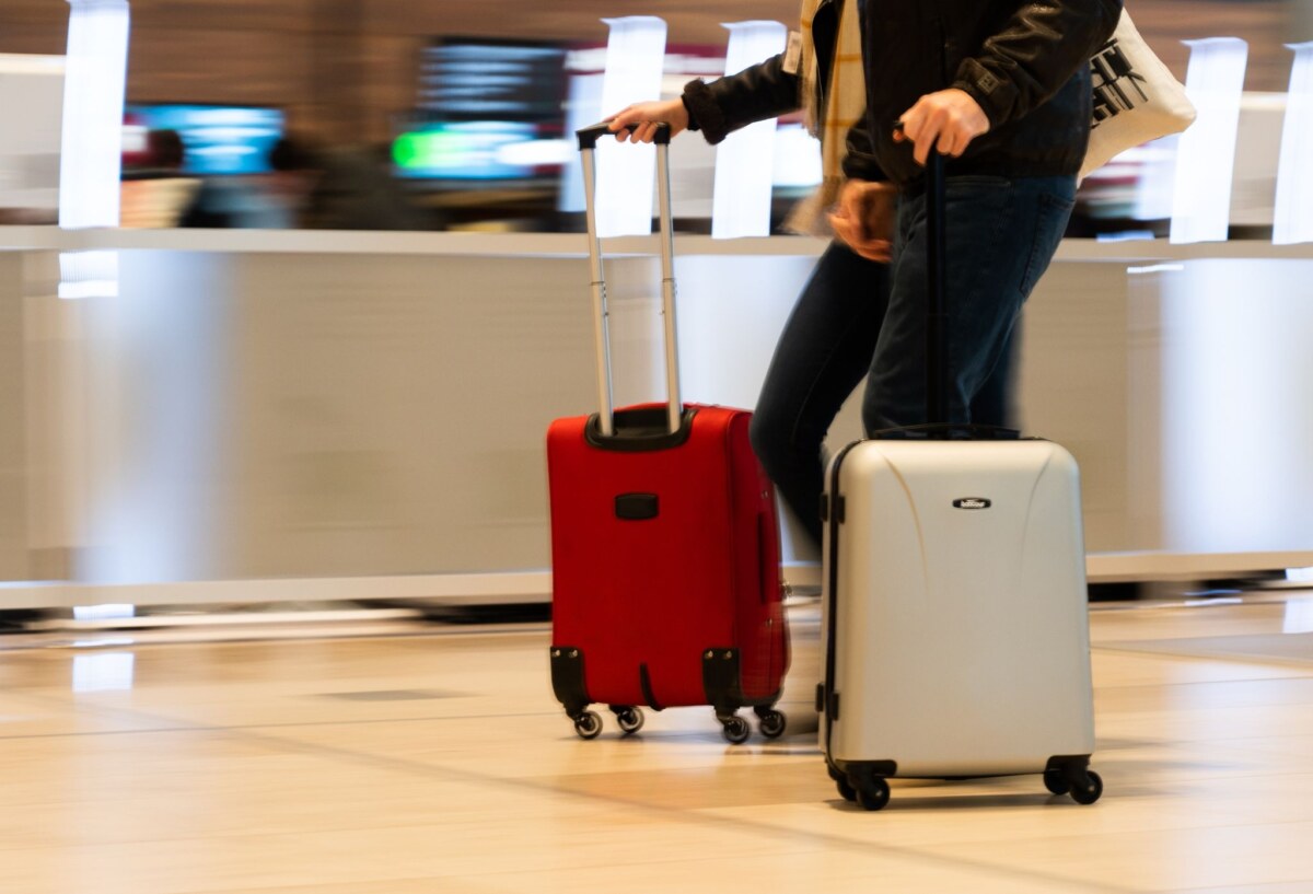 Menschen gehen im Terminal 1 am Flughafen Berlin Brandenburg mit ihren Trolleys durch die Haupthalle.