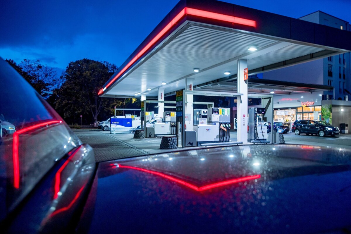 Autos stehen abends vor einer Tankstelle.