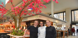 Ulrike Piecha (Mitte) und ihre Kollegen Mika Stuppi und Mo Scott vor dem Delikatessenstand in der Kreuzberger Marheineke-Halle. Bild: Stefan Bartylla