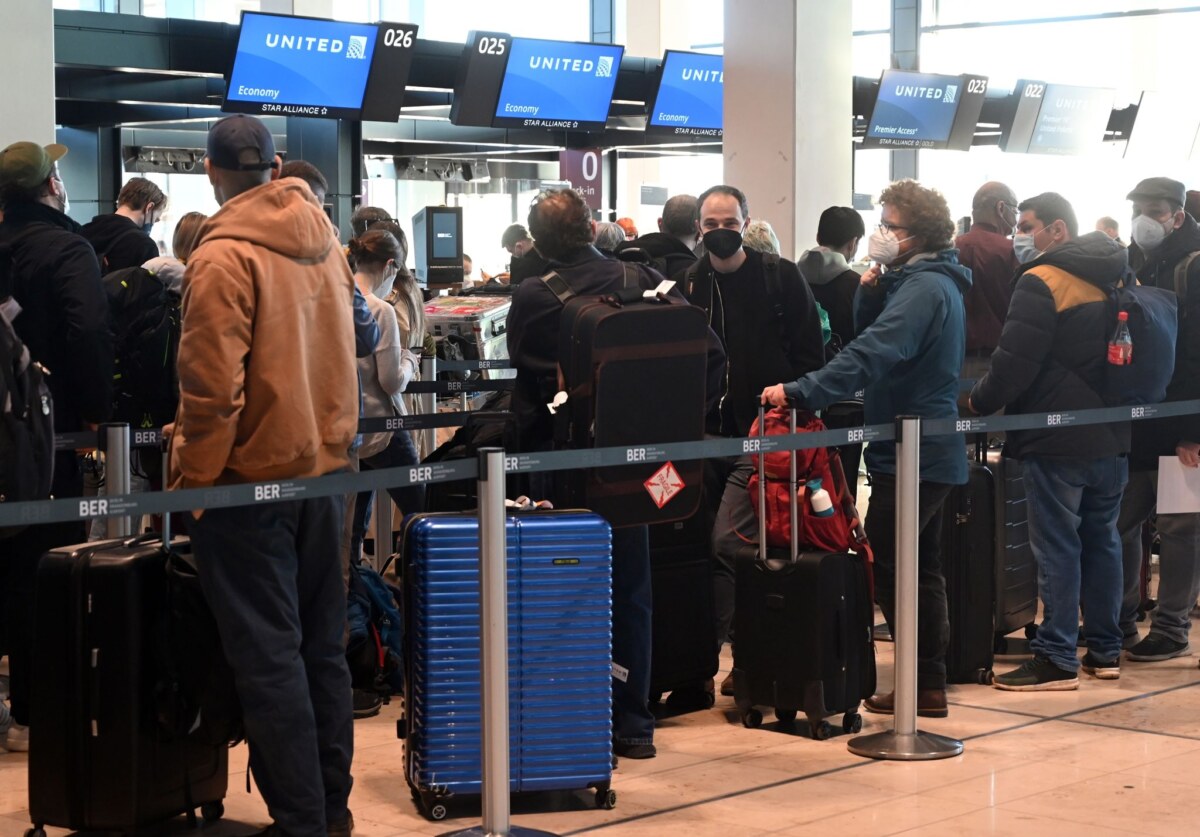 Fluggäste warten auf dem Flughafen BER vor den Check-in-Schaltern.