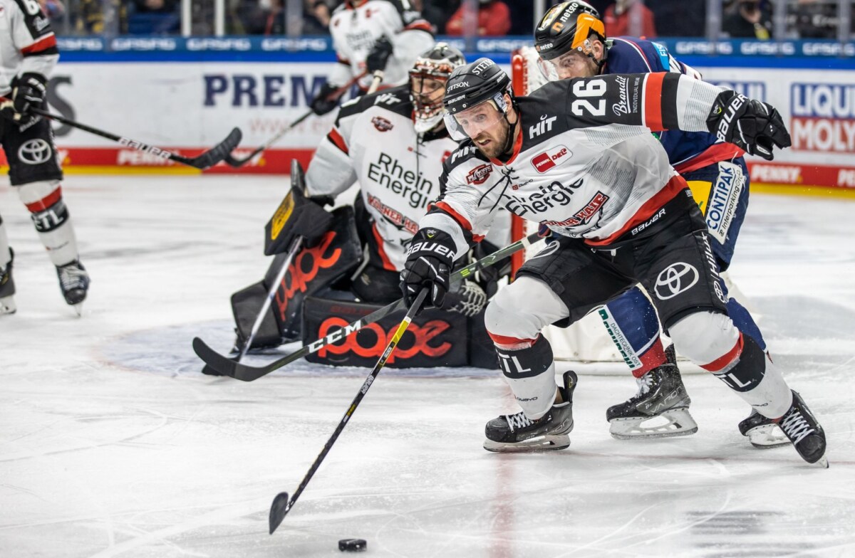 Davis McIntyre von Köln wird verfolgt von Berlins Yannick Veilleux (r).