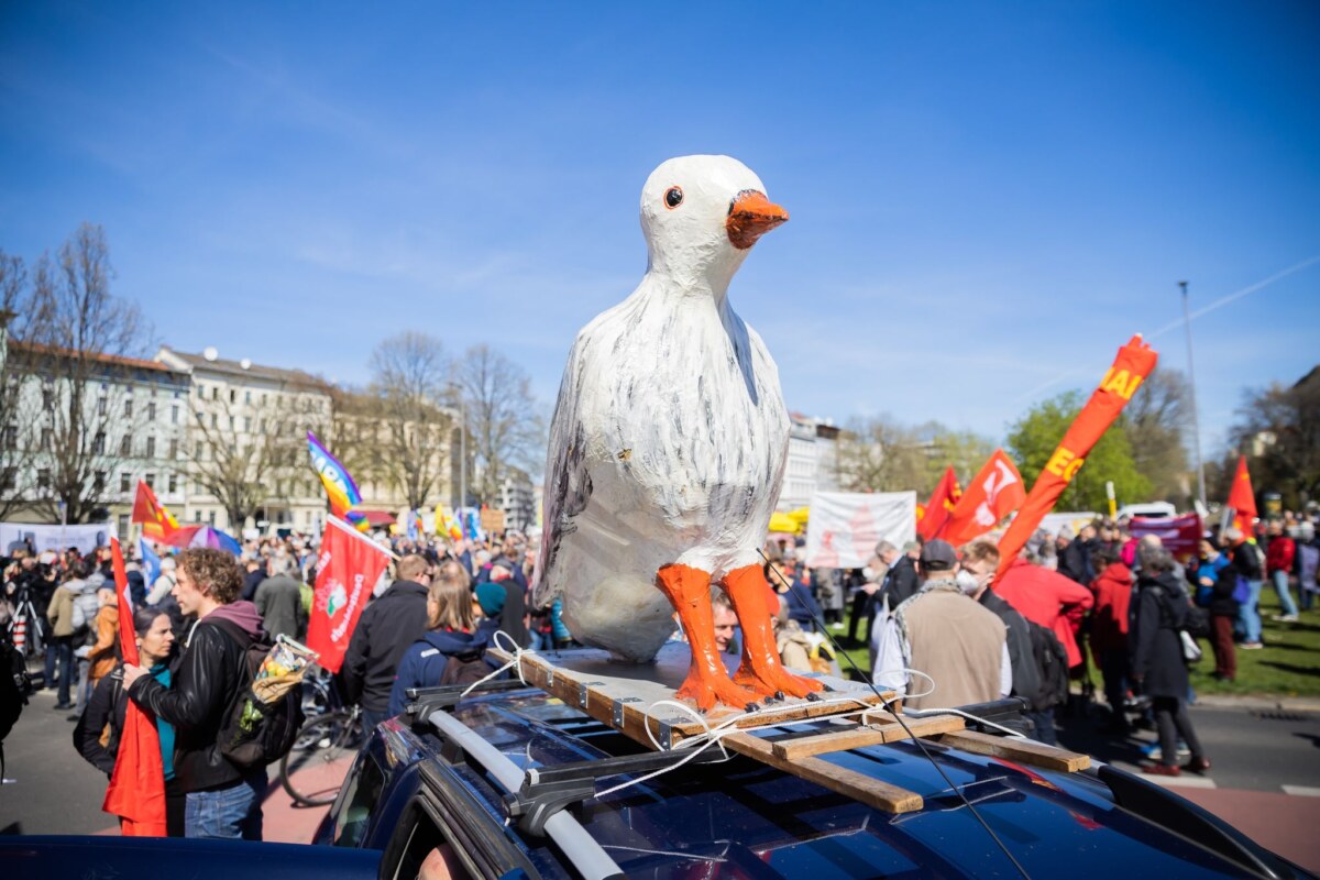 Eine Figur einer Friedenstaube sitzt beim Ostermarsch auf einem Autodach.