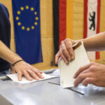 Mann wirft Stimmzettel bei Wahl in Wahlurne.