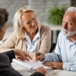 Senior couple signing a contract while having a meeting with insurance agent in the office.