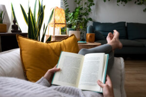 Frau liest Buch auf Sofa.
