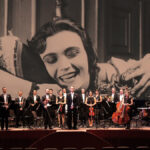 Orchestermusiker auf der Bühne vor einer Filmszene.