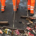 Drei Männer kehren die Straße