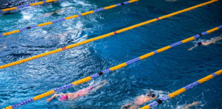 Symbolbild Schwimmhalle Schwimmende Sportler:innen / Schwimmer:innen in Bahnen. *** Symbolic image indoor swimming pool