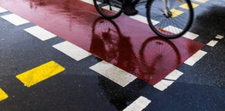 Ein Radfahrer auf dem Radweg spiegelt sich in der nassen Strasse in Berlin, 03.02.2022. Berlin Deutschland