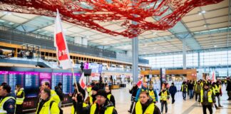 Teilnehmer einer Demonstration zum Warnstreik am Flughafen Berlin-Brandenburg BER laufen durch das Terminal 1.