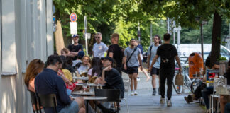 Menschen sitzen im Sommer vor einem Restaurant.