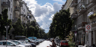 Junge Frau mit einem Kinderwagen überquert die Schliemannstraße in Berlin-Prenzlauer Berg.