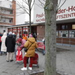 Menschen stehen Schlange vor Tafel-Ausgabestelle.