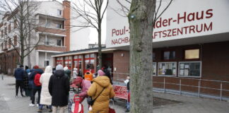 Menschen stehen Schlange vor Tafel-Ausgabestelle.