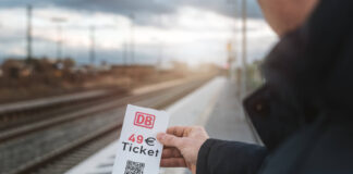 Symbolbild für das Deutschlandticket. Mann hält Zettel mit Aufschrift "49-Euro-Ticket" in der Hand.