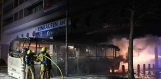 Einsatzkräfte der Feuerwehr löschen in der Silvesternacht an der Sonnenallee im Bezirk Neukölln einen brennenden Bus, der von Unbekannten angezündet worden war.