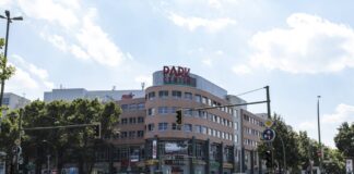 Einkaufszentrum Park Center mit rötlich-hellbrauner Fassade und Glasfronten hinter viel befahrener Kreuzung