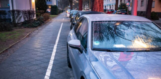 Blaues Auto steht auf Radstreifen eines Gehwegs. Dahinter sind weitere Autos zu sehen