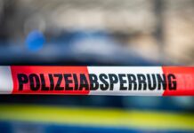 Ein Absperrband mit der Aufschrift «Polizeiabsperrung» ist vor einem Polizeiwagen aufgespannt.
