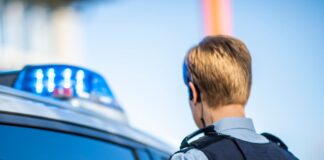 Eine Polizistin steht vor einem Streifenwagen.