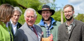 Charles, damaliger Prinz von Wales (3.v.l.), hält bei dem Besuch des Bio-Bauernhofs einen Bruderhahn in den Händen.