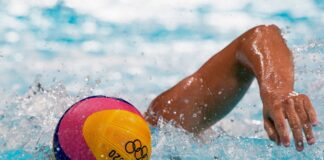 Ein Sortler schwimmt zum Wasserball.