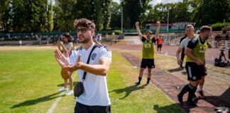 Elias Nerlich, FIFA-Streamer, steht am Spielfeldrand und klatscht.