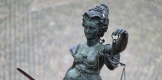 Eine Statue der Justitia hält eine Waage und ein Schwert in der Hand.