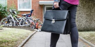 Eine Gerichtsvollzieherin geht mit ihrer Aktentasche zu einer Wohnung.