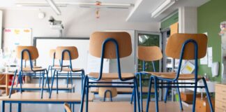 Stühle stehen in einem Klassenzimmer auf den Tischen.