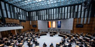 Abgeordnete stehen im Plenarsaal des Berliner Abgeordnetenhauses.