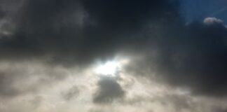 Die Sonne kommt nur kurzzeitig hinter einer dunklen Wolkendecke hervor.