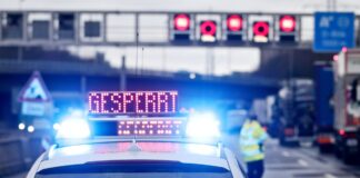 Auf einem Polizeifahrzeug leuchtet die Aufschrift «Gesperrt».