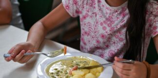 Eine Schülerin sitzt beim Mittagessen in der Mensa einer Schule.