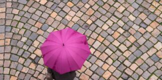 Eine Frau geht mit einem Regenschirm auf einer Straße entlang.