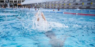 Ein Kind springt in einem Schwimmbad ins Becken.