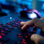 Ein Mann sitzt am Rechner und tippt auf einer Tastatur.