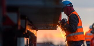 Ein Arbeiter führt auf einer Baustelle Schweißarbeiten an einer Brücke aus.