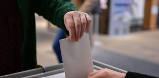 Ein Wähler steckt bei einer Wahl seinen Wahlzettel in eine Urne.