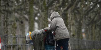 Eine obdachlose Frau schiebt ihr Hab und Gut in einem Einkaufswagen.