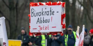 Ein Landwirt hält während der Kundgebung vor dem Brandenburger Tor ein Schild mit der Aufschrift «Bürokratie-Abbau! Jetzt» hoch.