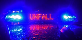 "Unfall" in roten LED-Leuchtbuchstaben steht zwischen zwei Blaulichtern auf dem Dach eines Polizeiwagens.