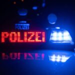 Zwei Polizisten stehen im Rahmen eines Fototermins vor einem Polizeifahrzeug.