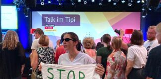 "Stop the Genocide" steht auf einem Transparent, dass eine Frau während einer Veranstaltung mit Außenministerin Baerbock im Rahmen der Demokratiefestets anlässlich des Jubiläums 75 Jahre Grundgesetz hält.