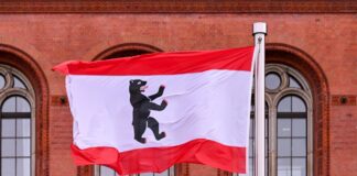 Die rot-weisse Fahne des Landes Berlin mit dem Berliner Bär weht vor dem Roten Rathaus.