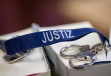 Ein Schlüsselanhänger mit dem Wort «Justiz» und Mini-Handschellen liegen auf zwei Gesetzbüchern.